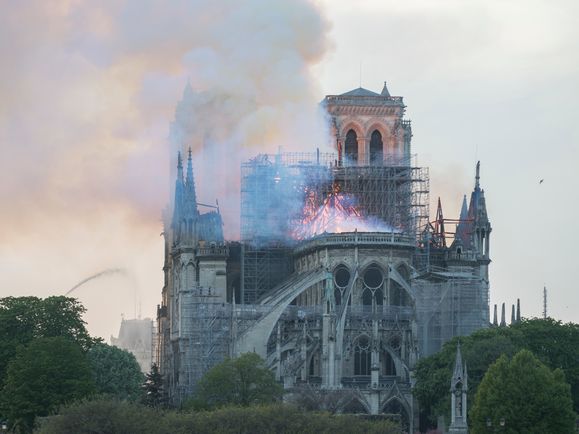 Rauch und Flammen beim Brand der Kathedrale Notre-Dame in Paris am 15. April 2019. Ein Wasserstrahl ist auf die Kirche gerichtet.